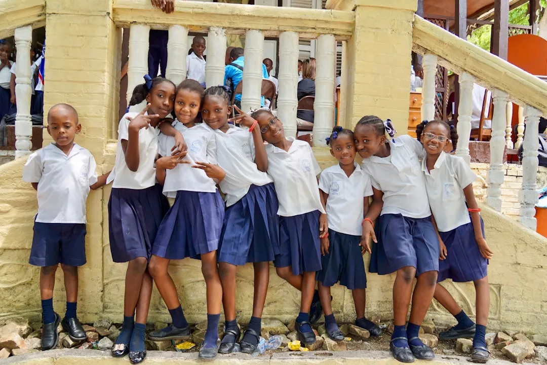 Un grupo de escolares con uniforme posa sonriendo junto a una escalinata.