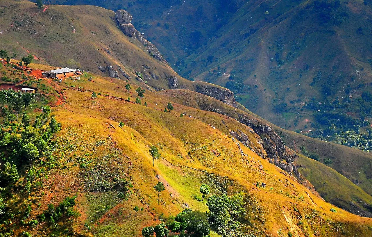 Montañas de Haití al atardecer, con laderas doradas y una casa aislada entre los cultivos.